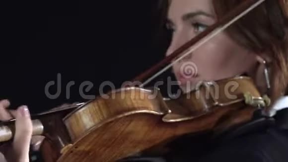 女孩在小提琴的琴弦上鞠躬黑色背景关门视频的预览图