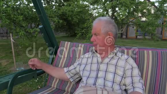 老人和白发老人坐在花园里荡秋千喝着水视频的预览图