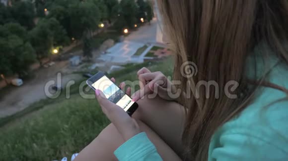 这个黑发女孩使用智能手机滚动和调整照片视频的预览图