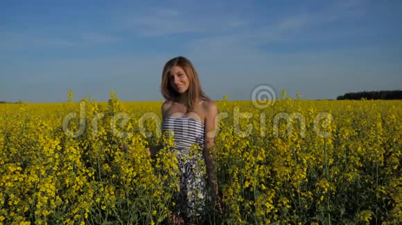 微笑的黑发女孩站在黄色的花丛里亲吻视频的预览图