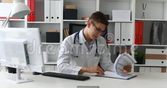 年轻的医生在工作场所看文件视频的预览图