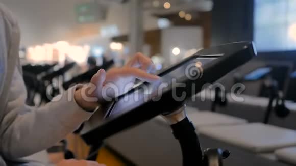 女性手使用触摸屏显示地板站立黑色平板电脑亭视频的预览图