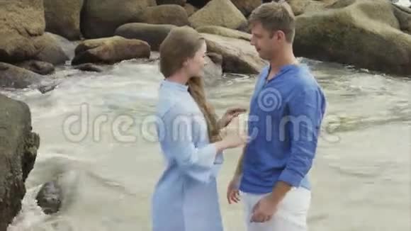 一个女孩在大石头的背景下拥抱一个男人在海上接吻视频的预览图
