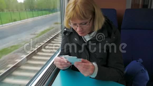 一个女人坐在窗边的高速列车上检查车票视频的预览图