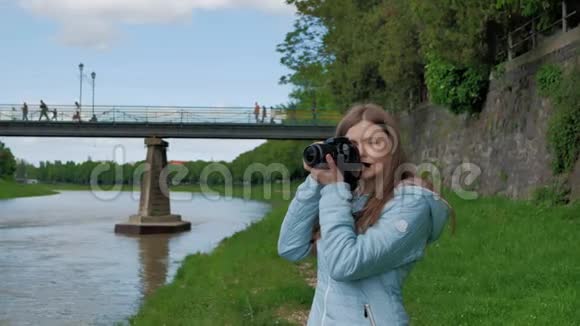 在河边的一个漂亮的小女孩用专业的照相机拍照桥和老式墙视频的预览图