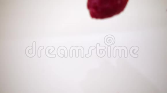 一颗红色草莓缓慢地落入牛奶中视频的预览图