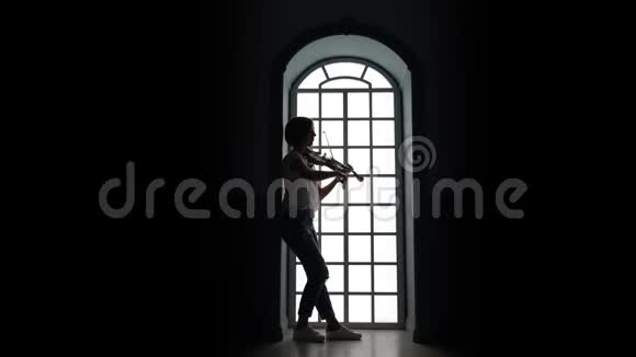 女孩用手指指着窗户拉小提琴剪影视频的预览图