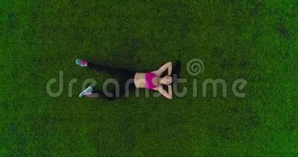 运动妇女在锻炼后躺在草地上休息上面的风景框架高度视频的预览图