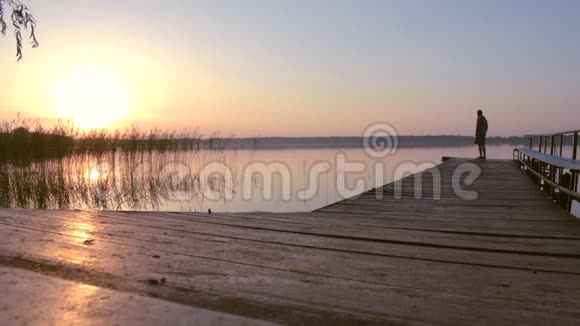 人的剪影沿着湖中的码头一直走到日出视频的预览图