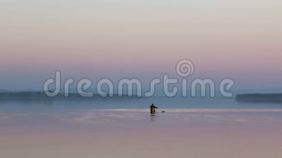 一名渔民在俄罗斯普里莫尔斯基克拉伊的阿穆斯基湾安装渔具背景是一片红色的日落天空视频的预览图