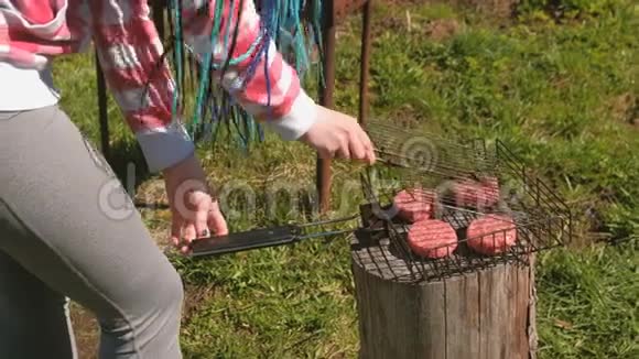 无法辨认的年轻女人用排骨把烤架关上特写双手她穿着格子粉色衬衫和蓝色视频的预览图