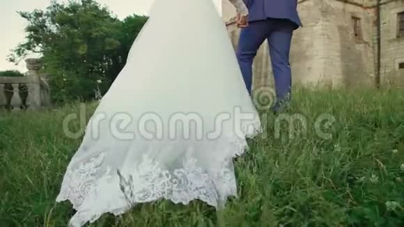 新娘的婚纱在城堡附近和新郎走在一起慢慢地视频的预览图