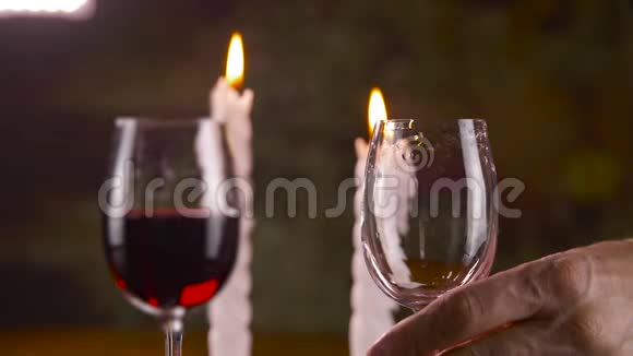 在蜡烛背景下男人用杯子倒红酒视频的预览图