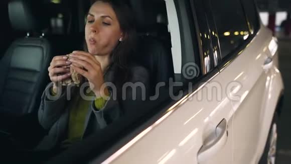 在停车场坐在车里吃三明治的女人现代忙碌生活的概念视频的预览图