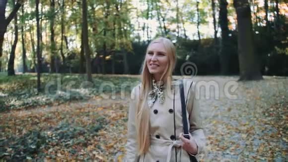 秋天美丽的金发女孩在公园散步视频的预览图