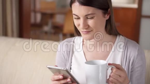 微笑的职业妇女在家里用手机喝咖啡家庭办公概念视频的预览图