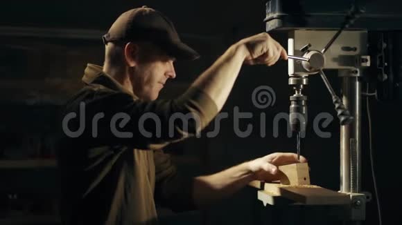 一个穿着特殊制服的专业木匠正在车间的木块上钻一个洞视频的预览图