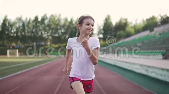 小女孩喜欢慢跑的肖像那孩子沿着体育场的跑道跑视频的预览图