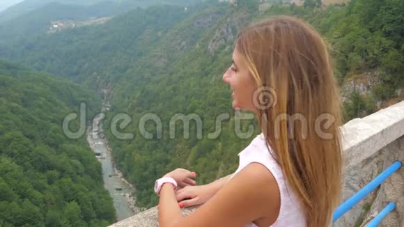 年轻女子望山立在一座大峡谷的桥上视频的预览图