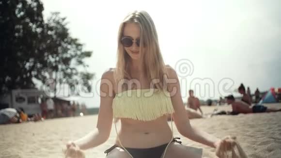 年轻的金发女人坐在海滩上玩得很开心视频的预览图