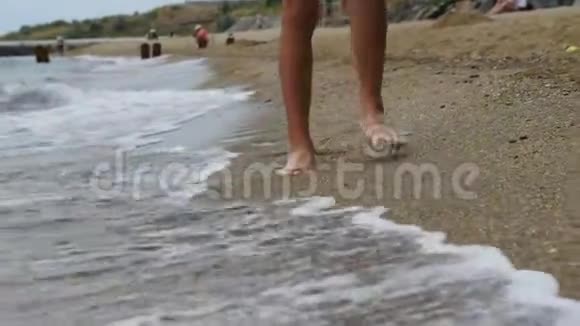 男孩正拿着电话沿着沙滩上的金沙散步视频的预览图