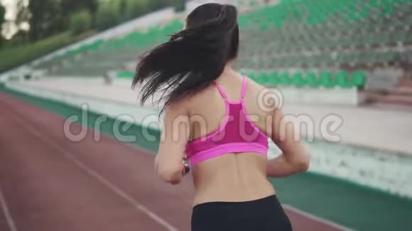 在体育场慢跑后面的景色穿运动装的年轻女孩跑步慢动作视频的预览图