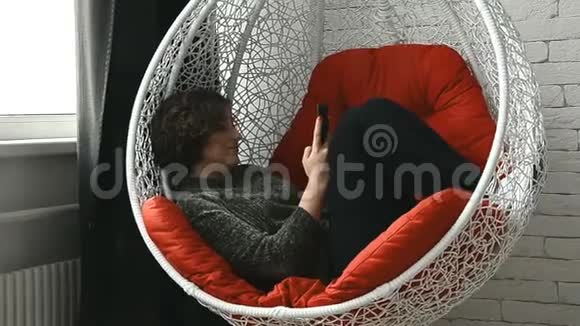 一个女人手里拿着手机躺在椅子上视频的预览图