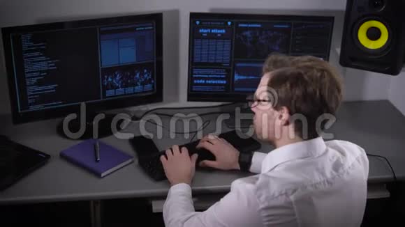 侧面看一个年轻的自由职业者穿着白色衬衫和智能手表在家里的电脑工作独立程序员视频的预览图