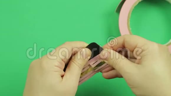 女用手在绿色背景上包上粉红色丝带图案视频的预览图