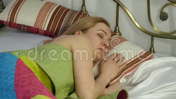 金发女人醒来看着闹钟把它藏在枕头下面4K视频的预览图