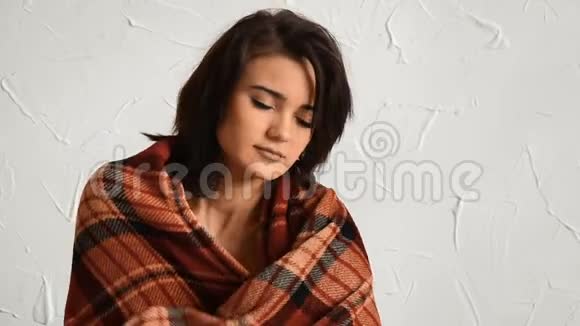 迷人的黑发女人站在墙边裹着温暖的毯子视频的预览图