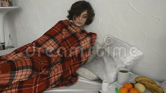 一个生病的女人躺在毯子下面测量体温视频的预览图
