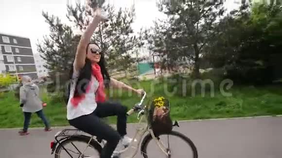 骑自行车的快乐年轻女人的肖像她的自行车篮子里有花和一个包她喜欢这次旅行视频的预览图