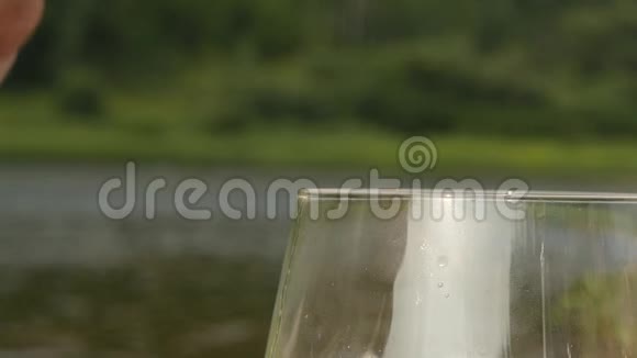 在自然背景下将冷啤酒倒入啤酒罐的玻璃中慢动作视频的预览图