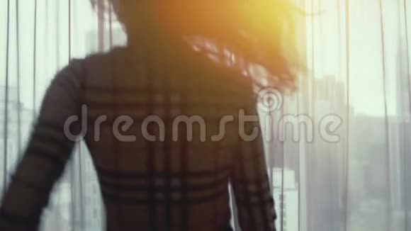 年轻漂亮的黑发女人跑到窗户前揭开窗帘欣赏着家中窗户上的日落景色视频的预览图