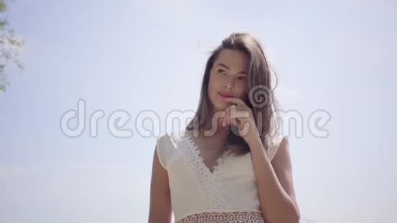 一位美丽的少女一头深色长发穿着白色的夏装站在她的肖像上视频的预览图