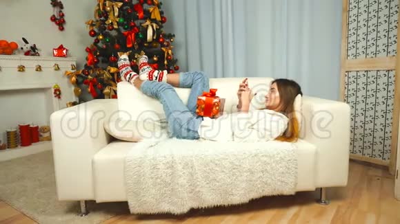 女孩在圣诞树附近用手机写问候短信视频的预览图
