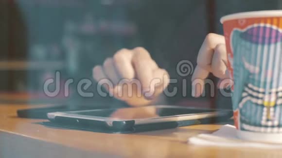 有人在咖啡厅的窗户里用平板电脑喝咖啡视频的预览图