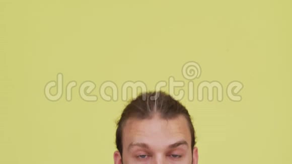 男人在镜头前绑着头发在柠檬色背景特写镜头上的幽默表情情感概念视频的预览图