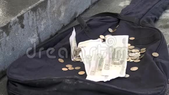 钱落在户外城市人行道上的黑色吉他箱上把纸币和硬币放在黑色空的视频的预览图