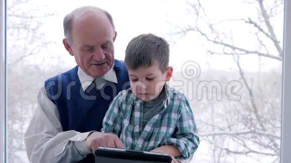 家庭教育爷爷和孙子在室内玩网络游戏视频的预览图