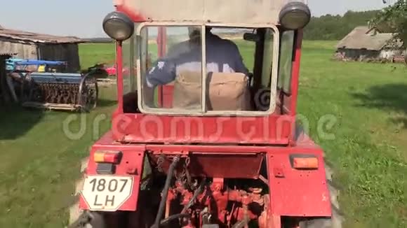 农夫开着旧红拖拉机穿过草地视频的预览图