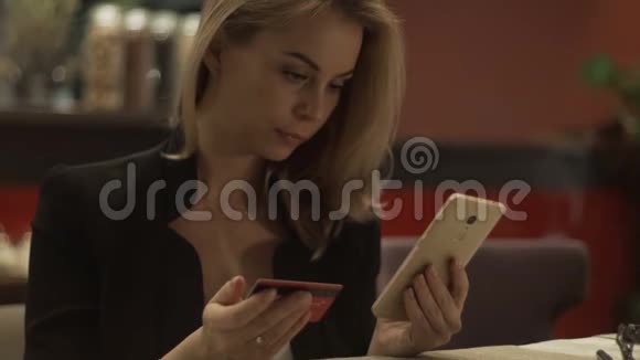 使用塑料银行卡和手机进行网上购物的美女视频的预览图