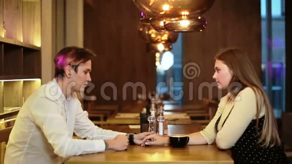 年轻一对情侣正坐在咖啡馆里开心地笑着喝着咖啡视频的预览图