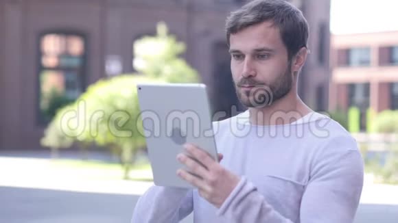 帅哥在平板电脑上浏览互联网而站在外面视频的预览图