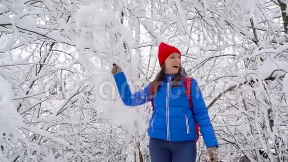 女人在玩她在摇动树枝雪落在她身上晴朗的晴朗的霜冻天气慢慢视频的预览图
