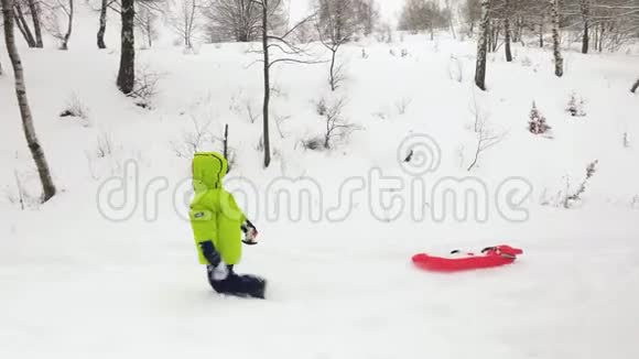 冬天的一边跟着小孩子在雪场上拉着红色的雪橇儿子或女儿雪上雪橇家庭成员视频的预览图