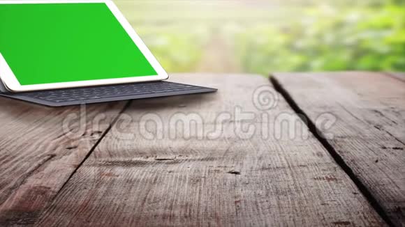 绿色屏幕平板电脑户外木桌上的平板电脑和键盘更换图像的绿色屏幕画面视频的预览图