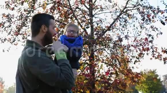 父亲在城市公园玩和抱儿子快乐爸爸一个男孩抱着一个秋日一起户外日落视频的预览图