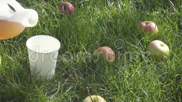 在草地上缓慢的运动是苹果果汁被倒进玻璃杯里视频的预览图